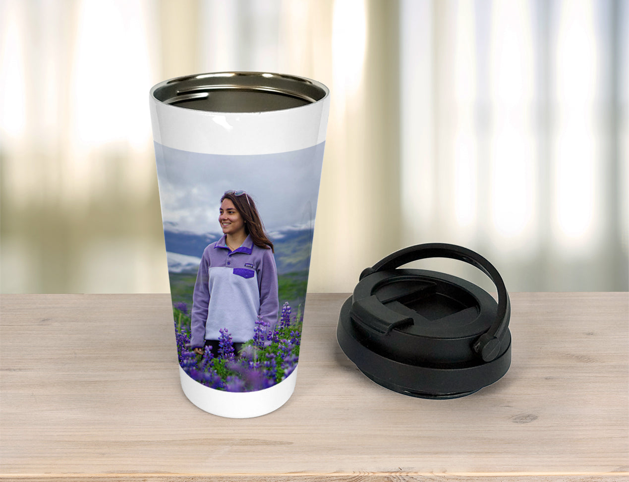 A Custom Travel Mug that is showing a user's image and standing on table with lid taken off
