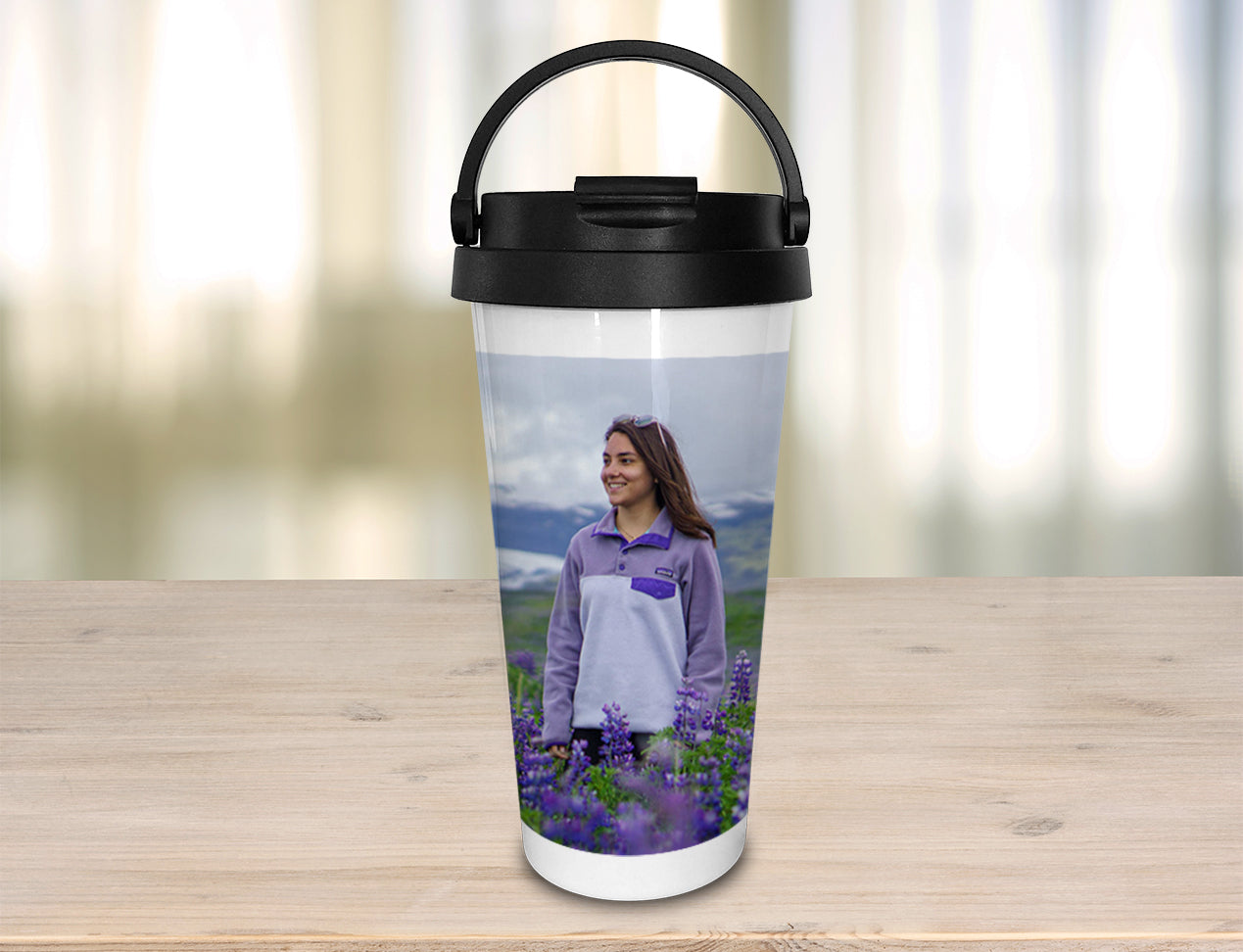 A Travel Mug personalised with an image standing on a table