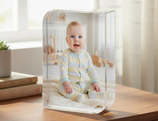 Clear acrylic block with a photo of a baby sitting on a wooden surface.