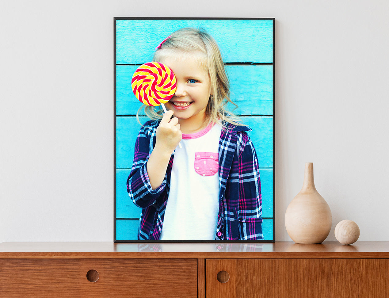 Poster with a Frame showing a girl.  Displayed on a mantlepiece and with a black frame.
