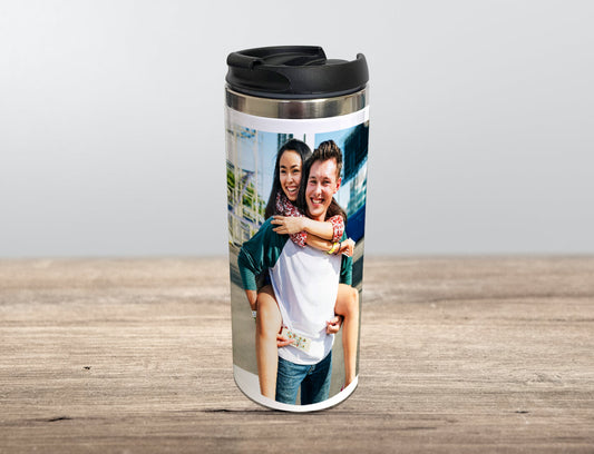 A custom stainless steel thermal mug with a custom photo print of two people on it, placed on a wooden surface.